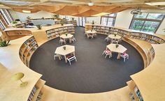 an aerial view of a library with tables and chairs in the center, surrounded by bookshelves