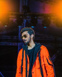 a man in an orange jacket and sunglasses on stage