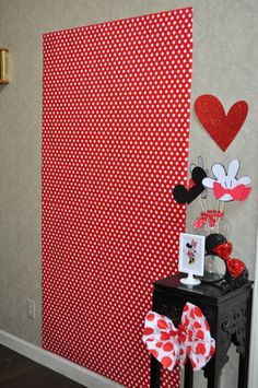 a mickey mouse themed room with red and white polka dot wallpaper, minnie mouse decorations, and heart shaped balloons