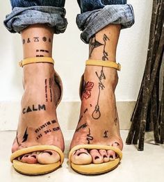 the legs and ankles of a woman with tattoos on her feet, both wearing yellow sandals