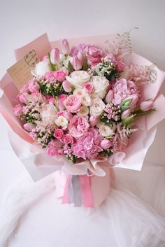 a bouquet of pink and white flowers is wrapped in paper