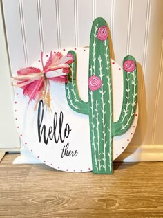 a wooden sign that says hello there is a cactus on it and the words hello there are