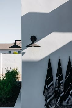 three black and white towels hanging on the side of a building next to a lamp