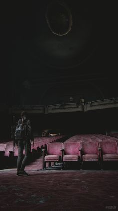 a person standing in the middle of a room filled with pink couches and chairs