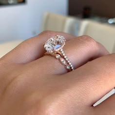 a woman's hand with a diamond ring on top of her finger and the other hand holding an engagement ring