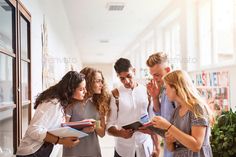 group of people standing around each other looking at something on a clipboard in an office