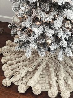 a crocheted christmas tree skirt is on the floor next to a pine tree