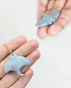 a hand holding a tiny dolphin necklace and a small dolphin keychain in it's palm