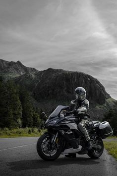 a man riding on the back of a motorcycle down a road