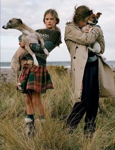 two women standing next to each other with dogs on their shoulders and one woman holding a dog in her arms