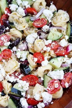 a salad with cucumbers, tomatoes and feta cheese in a wooden bowl