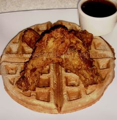 chicken and waffles on a white plate next to a cup of black coffee