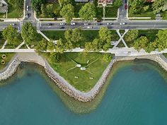 an aerial view of a park and river with cars driving on the road next to it