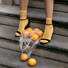 a person standing on some steps with oranges in their hand and one is wearing yellow socks