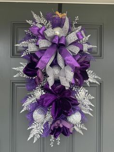 a purple and silver wreath hanging on the front door