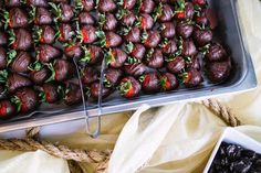 chocolate covered strawberries are on display in a metal tray and tied with twine