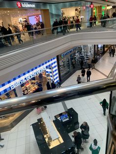 an overhead view of people shopping in a mall, with the escalator above them