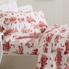 a bed with red and white bedspreads on top of it, next to a nightstand