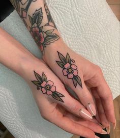 two women with matching tattoos on their hands holding each other's fingers and finger