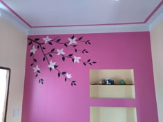 a pink wall with black and white flowers painted on the walls, along with shelving unit