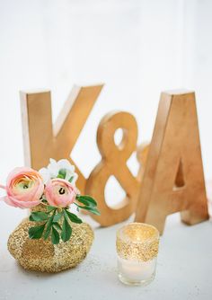 a vase filled with flowers sitting next to a wooden letter and candle holder on top of a table