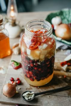 a jar filled with food sitting on top of a wooden table next to garlic and pepper