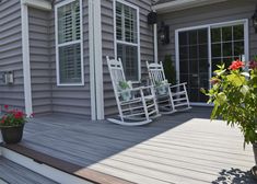 a porch with rocking chairs and potted plants