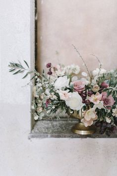 a vase filled with lots of flowers sitting on top of a window sill next to a wall