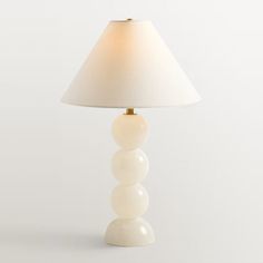 a white lamp sitting on top of a table next to a white wall and floor