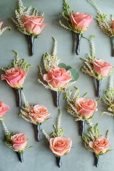 pink roses and baby's breath flowers are arranged on a gray tablecloth with greenery