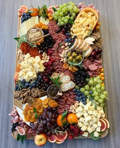 a platter filled with lots of different types of fruit and cheese on top of a table