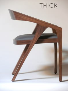 a wooden chair with black leather upholstered on the seat and back, in front of a white background