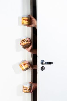 two hands holding jars of yogurt in front of an open door with the handles