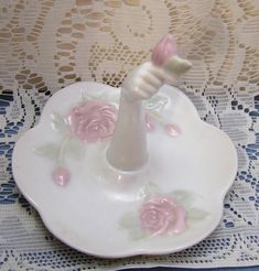 a small porcelain toothbrush holder on a lace doily with pink roses and leaves