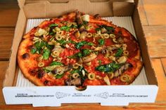 a pizza sitting inside of a box on top of a wooden table