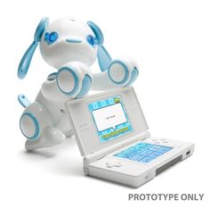 a white and blue toy dog sitting on top of a laptop computer next to it's keyboard