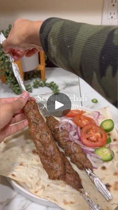 someone is cutting up some meat on a plate with tomatoes and cucumber slices