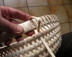 a person is holding a basket made out of wood and woven with white strips on it