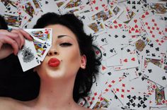 a woman laying down with playing cards in her mouth