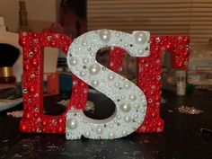 the letter s is decorated with pearls and other things to make it look like they are made out of glass beads