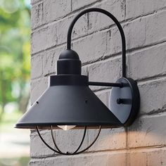 an outdoor wall light on the side of a building with a brick wall behind it