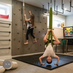 two children are playing on the climbing wall in their playroom, while one child is doing handstand