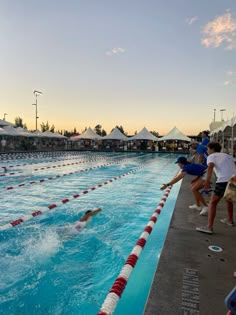 people are in the water at an outdoor swimming pool