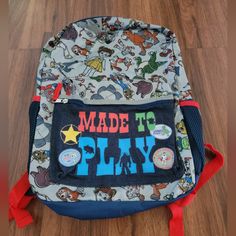 a back pack with the words made to play printed on it, sitting on a wooden floor