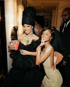 two women dressed in black and gold posing for the camera with one holding a candy bar