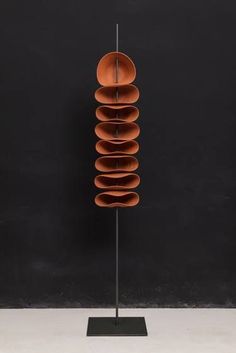 a sculpture made out of orange plates on a metal stand in front of a black wall