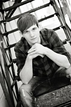 a young man sitting on top of a wooden chair