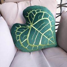 a green heart shaped pillow sitting on top of a white couch