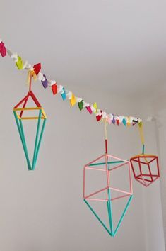 three colorful geometric ornaments hanging from a string in a room with white walls and flooring