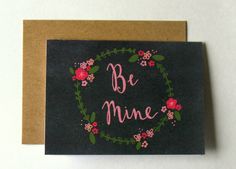 a card with the words be mine written in pink and green flowers on a black background